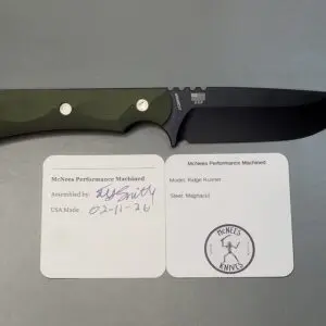 A fixed-blade knife with a green handle resting on two informational cards.