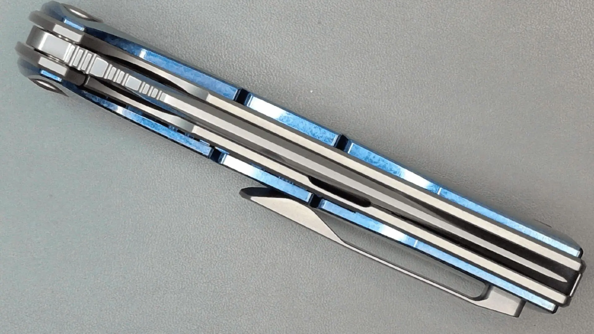Close-up of a folding knife with a blue patterned handle and polished blade.