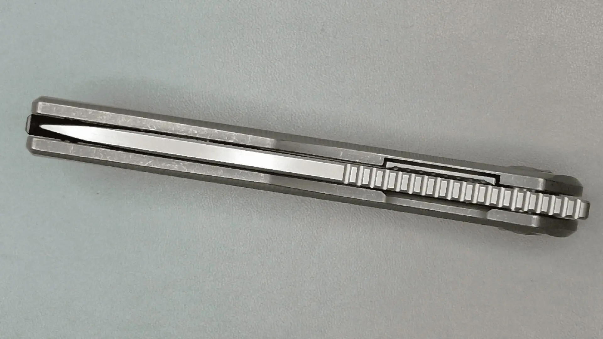 Close-up of a metallic pen with engraved markings on a gray surface.