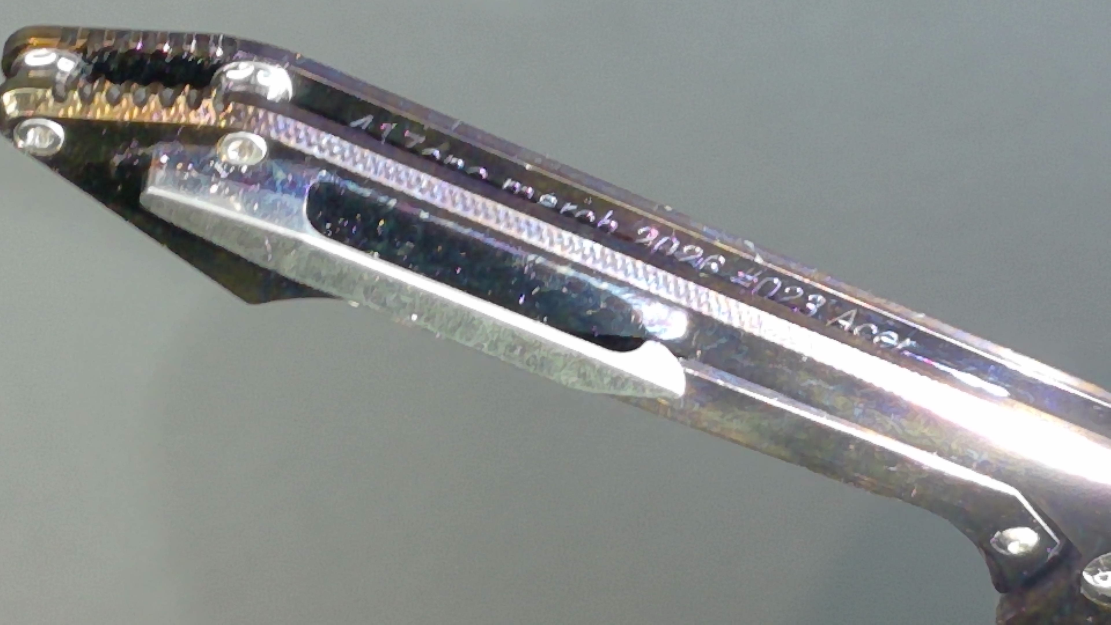 Close-up of a metal tool with engraved text and a slot.