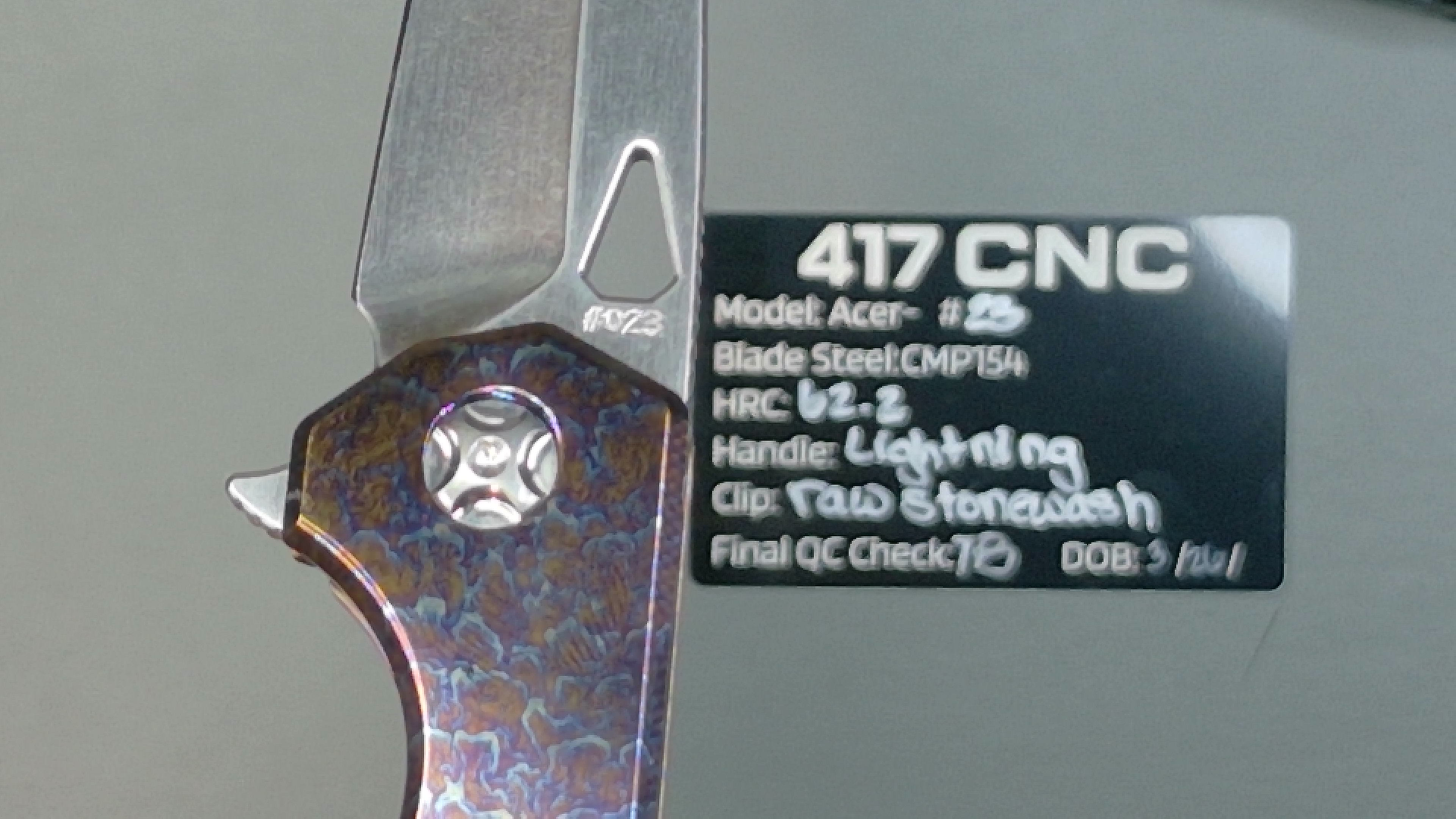 Close-up of a knife blade with model and manufacturing details engraved.