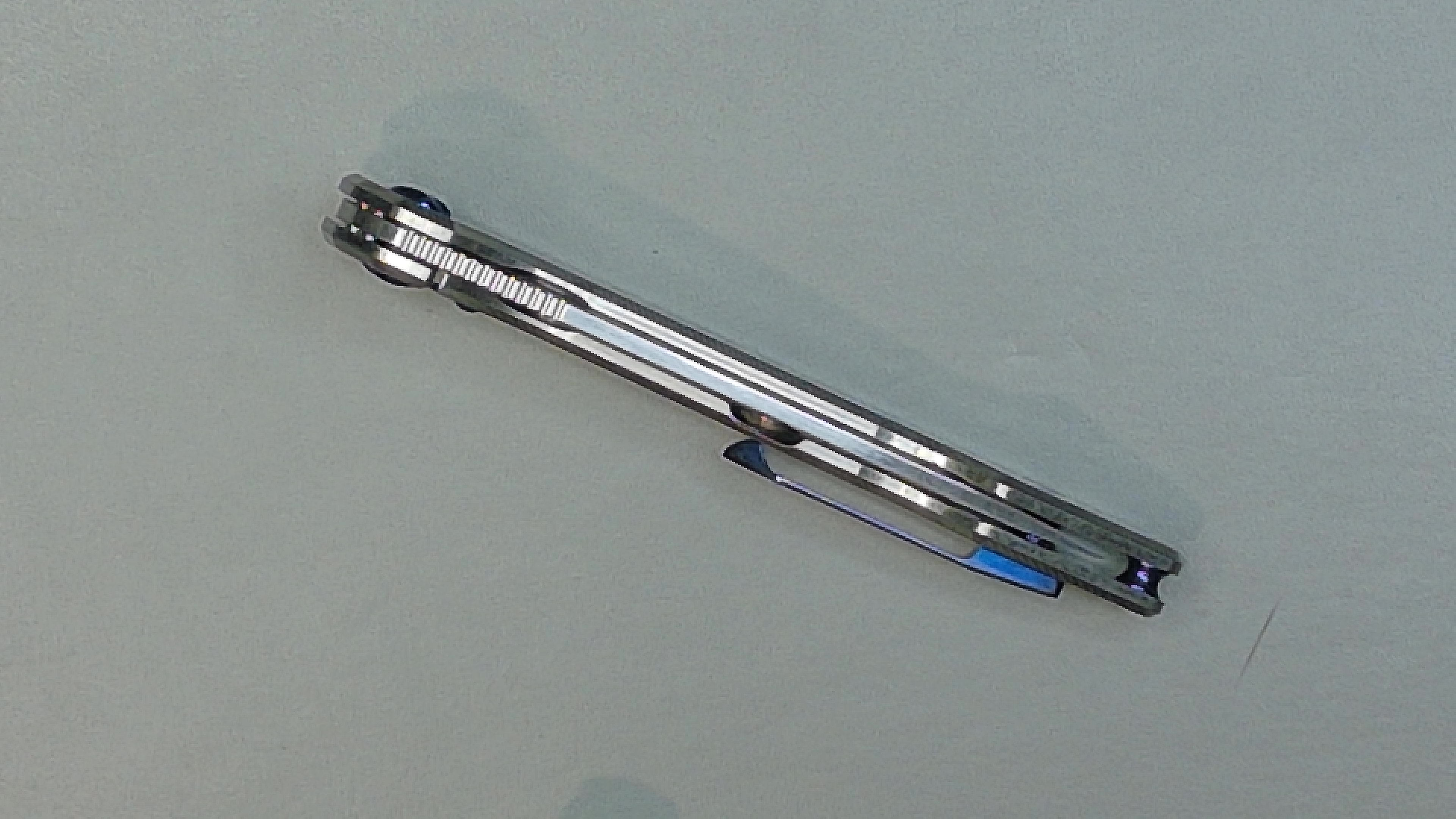 A black and silver foldable tripod stand on a grey surface.