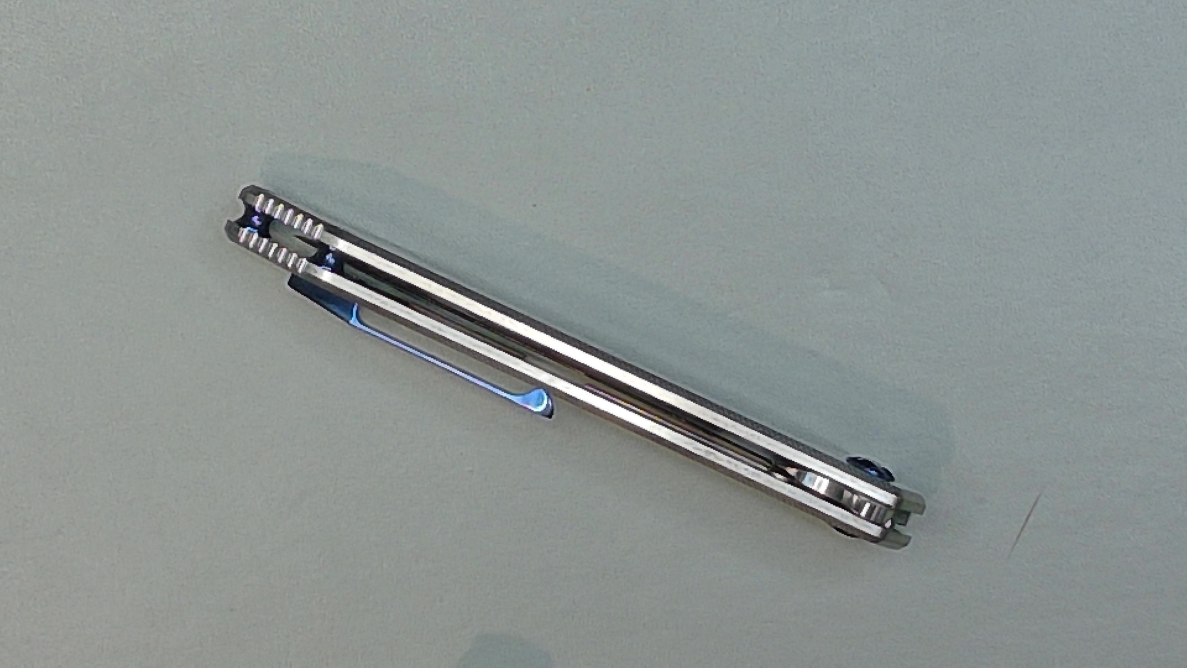 A sleek silver pen with a clip on a gray surface.