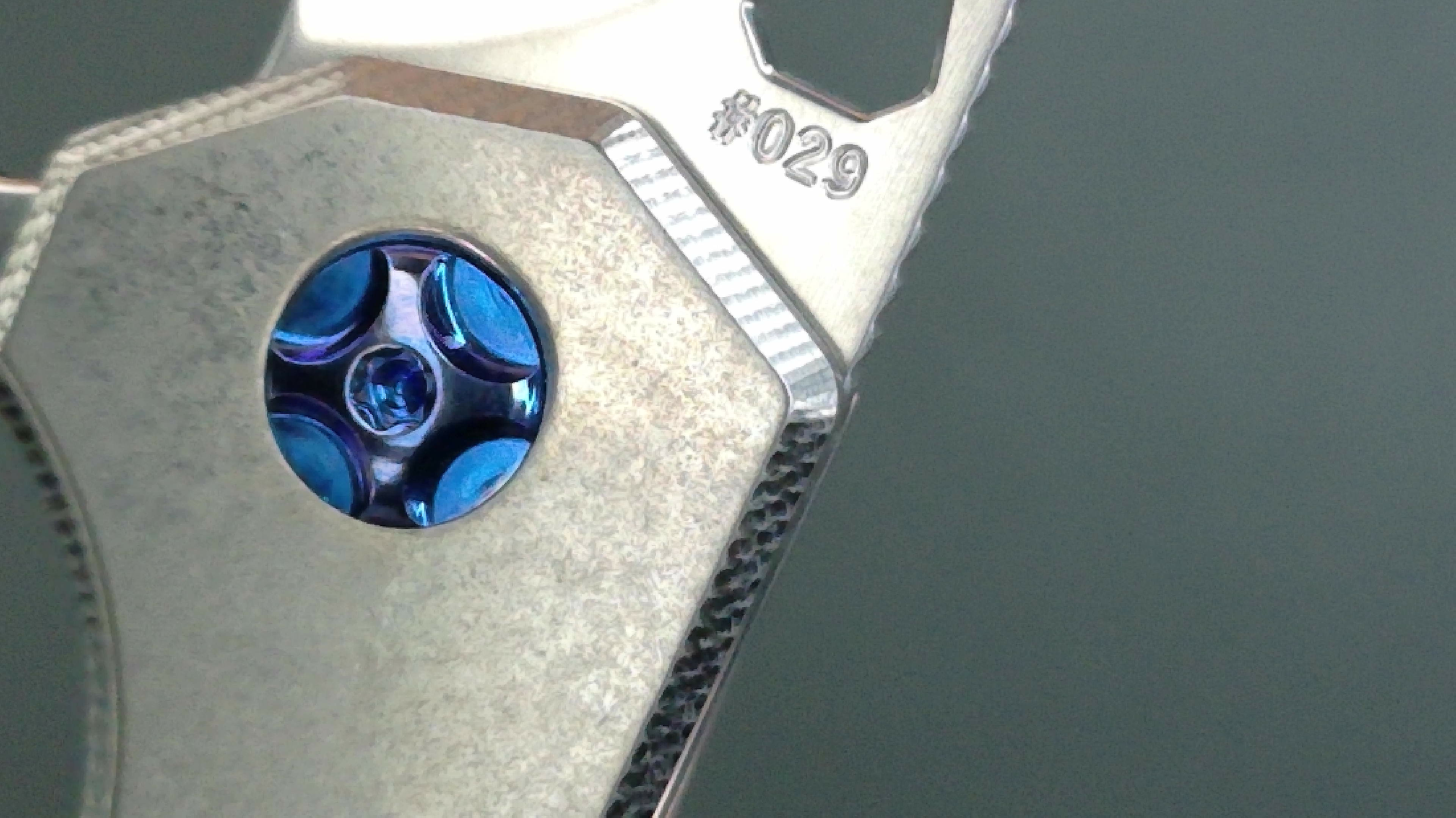 Close-up of a metal object with a blue screw and engraving.
