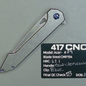 A silver folding knife with a metal handle on a textured surface.