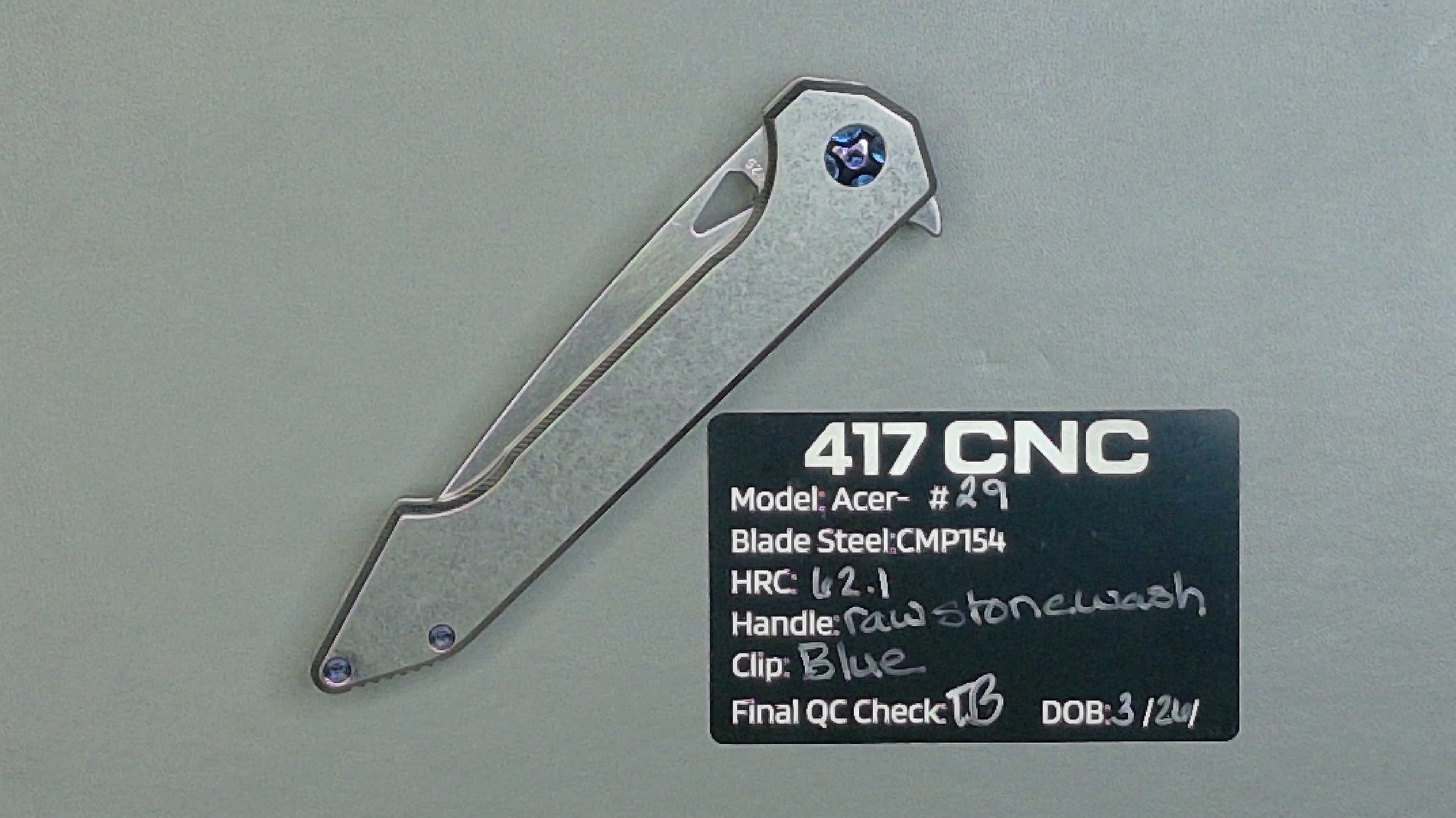 A silver folding knife with a metal handle on a textured surface.