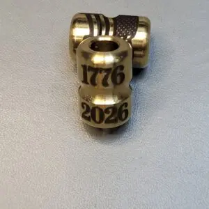 A brass bead engraved with '1776' and '2026'.